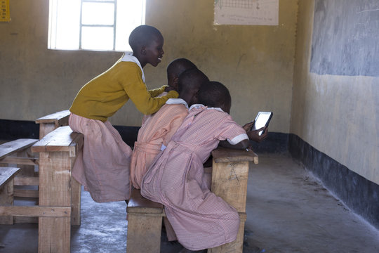 School girls in classroom, looking at tablet. Kenya, Africa.