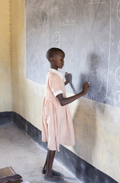 School girl writing on blackboard in classroom