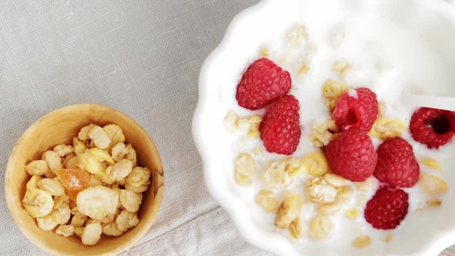 Healthy breakfast - muesli, granola, cereals, raspberry, yogurt. Top view. Slow pan.