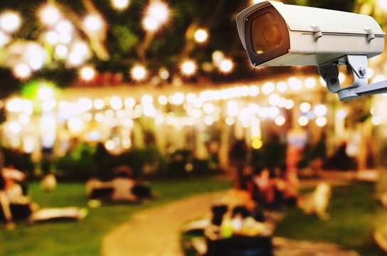 CCTV, security indoor camera system operating with blurred image of abstract night light bokeh of night festival in garden background, surveillance security technology concept
