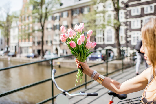 Holding a bouguet of pink tulips on the water channel and buildings background in Amsterdam