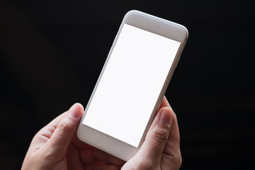 Mockup image of hands holding white mobile phone with blank screen with black background