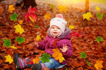 baby girl playing with autumn leaves