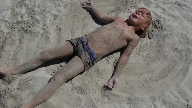  little blond boy playing at the beach