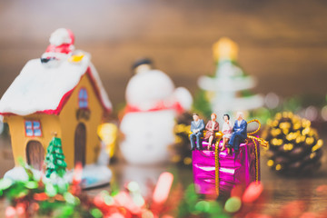 Miniature people on gift box with Christmas Day celebration background