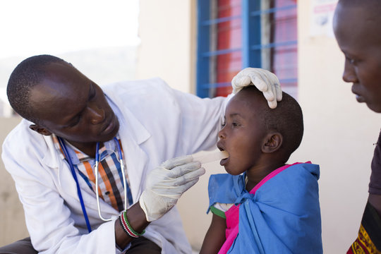 Doctor examining young girl's throat from the Maasai tribe