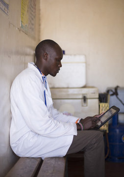 Doctor looking at tablet in clinic. Kenya, Africa.
