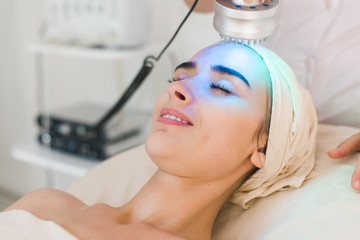 Young healthy woman with good skin doing cosmetic procedures in spa clinic. Light treatment.