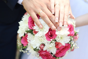 Obraz na płótnie Canvas hands of bride and groom on the bouquet