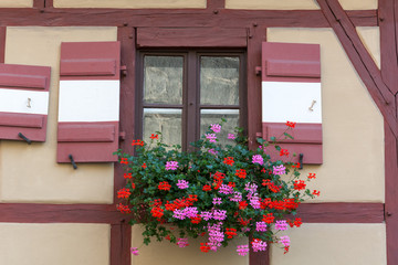 Half-timbered house with window shutters and flowers