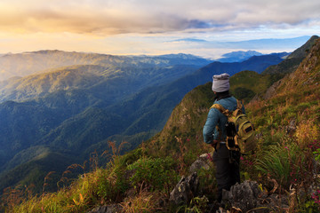 Fototapeta na wymiar A traveler on top of mountain, he standing on the rock watching a nice sunrise