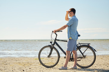 Obraz premium happy young man with bicycle on beach 