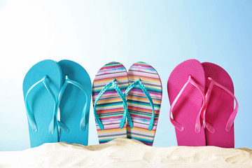 Colorful flip-flops on sand against color background. Summer vacation concept