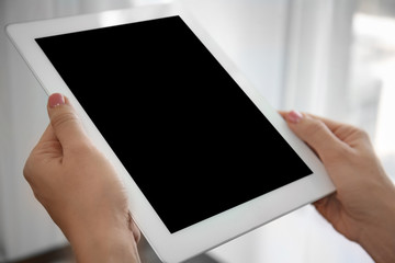 Young woman holding tablet near window