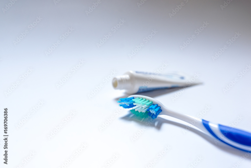 Wall mural toothbrush with toothpaste next to a tube of toothpaste against white background