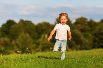 cute young boy runs over a meadow