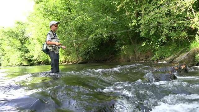 Young boy fly-fishing in river