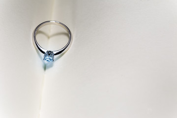 beautiful diamond ring on blank open book with heart shape shadow