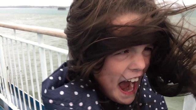 Young girl on windy ferry deck with crazy hair blowing in slow motion