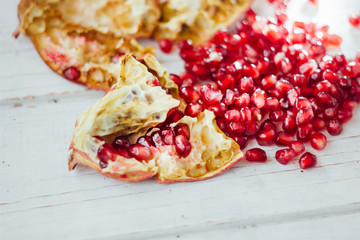 Pomegranate peel and seeds over white wooden background.