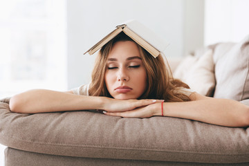 Young woman sleep on sofa with book on head