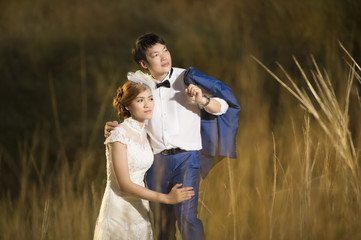 Asian couple with pre wedding sceen outdoor dry meadow on the hill and the sea at sunset is falling background.,thai lover