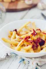 Poutine fries with tomato sauce and cheese on white table.