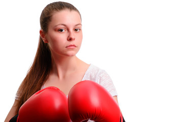 A young sports woman-boxer poses to the camera in red boxing gloves. She concentrates and standing in the battle rack