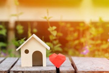 A house model and red heart with family love concept, on the wooden floor in public park.