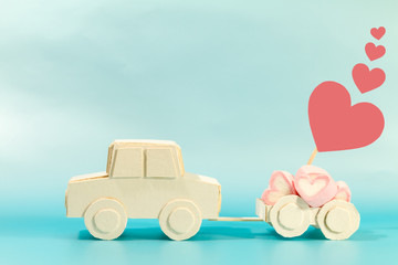 A car model transport marshmallows heart-shaped on blue background, for supporting when people get who lack of desire with love and Valentine's Day concept.