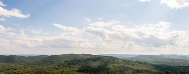 Panoramic photograph of rolling green mountains and a blue sky.