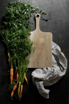 Fresh carrots on a dark background with chopping board