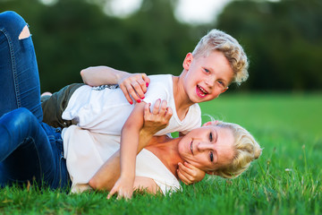 woman romps with her son on the grass