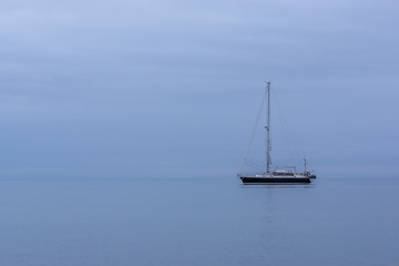 Fototapeta premium Sailing boat in blue twilight hour, alone in the ocean