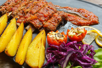 Close up. Pork Spare Ribs Barbecue with fried potato and fresh vegetable in black ceramic dish