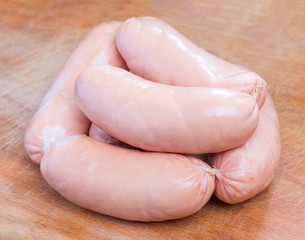a bunch of pink meat sausages on a cutting board closeup