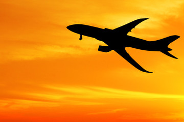 Silhouette of airplane taking off flight with orange sky background