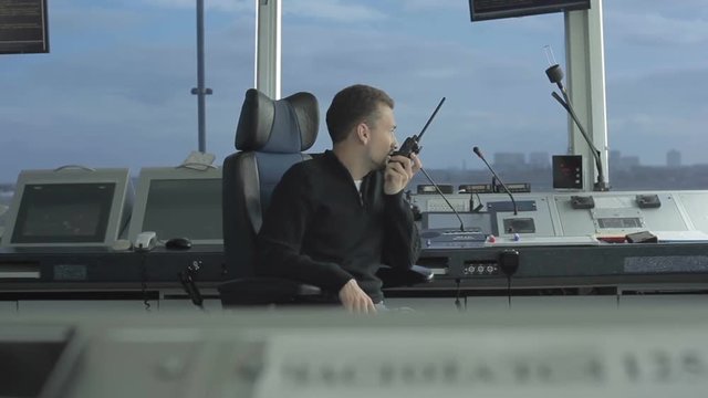 Professional dispatcher speaks with portable radio in control tower in airport