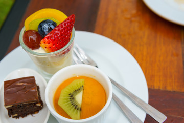 mixed fruit salad and yoghurt with spoon and fork. dessert.