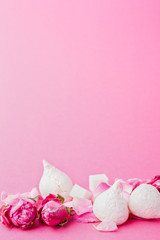 White meringues and roses buds at pink background