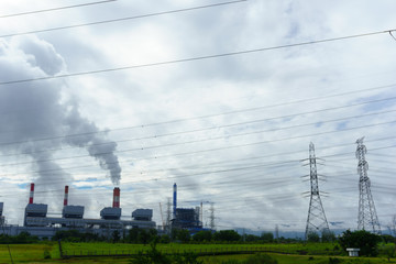 coal fire power plant release steam from stack with electrcity transmission line and cloudy sky.