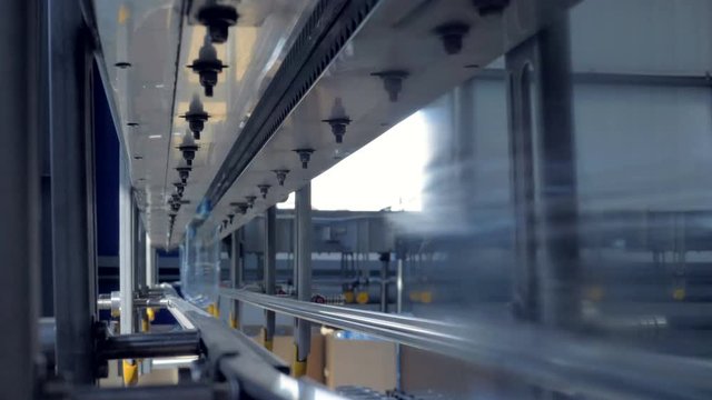 Empty PET bottles reflect natural light as they move on factory rails. 4K.