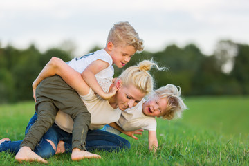 woman romps with her two sons on the grass