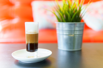 Latte macchiato or espresso macchiato with mock up plant on the table in cafe. coffee menu concept.
