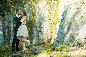 Pretty bride in short dress stands before a groom while he holds her tender