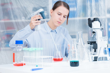 Fototapeta premium Woman Scientist Adding Liquid To Test Tube With Pipette In Lab