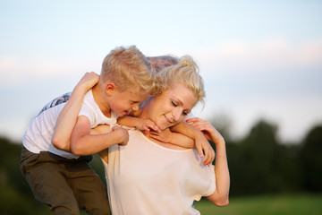 Fototapeta premium woman romps with her two sons on the grass