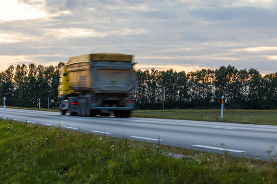 Speeding motion blur oncoming trucks with glowing lights on the highway after sunset. Abstract blur image background with copy space.