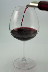 Taça de vinho sendo servida com vinho tinto 