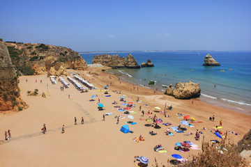 Fototapeta na wymiar Aerial top view Dona Ana Beach in Lagos. Summer scene with local families, young people and tourists relaxing, enjoying swimming in Atlantic ocean on hot day. Algarve region, south Portugal, Europe